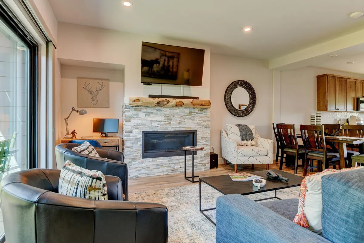 A welcoming open-concept living and dining area with a cozy fireplace, large TV, comfortable sofa, and a stylish dining table. The space is designed for both relaxation and group entertainment, making it ideal for family movie nights or casual gatherings.