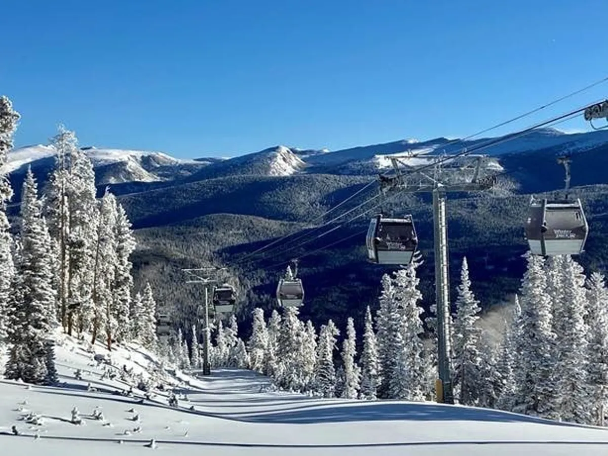 A panoramic winter scene showcasing snow-covered trees, ski lifts ascending the mountain, and people skiing and snowboarding. The sun rises over the mountains, and a cozy lodge sits at the resort base, illustrating both adventure and relaxation.